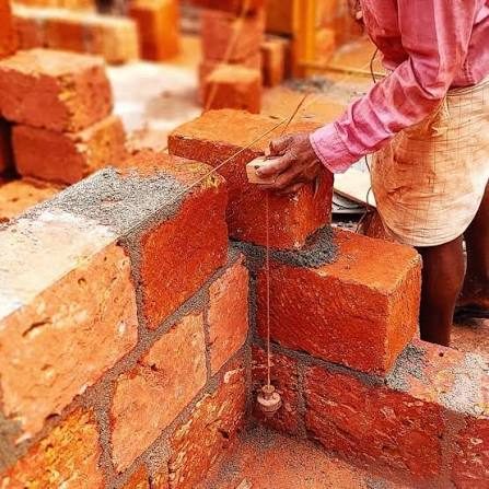 Mason laying bricks with plumb line